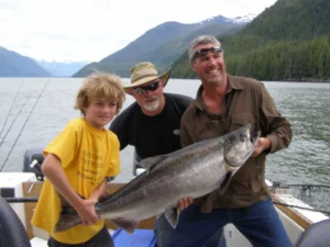 3 men holding a huge salmon they just caught